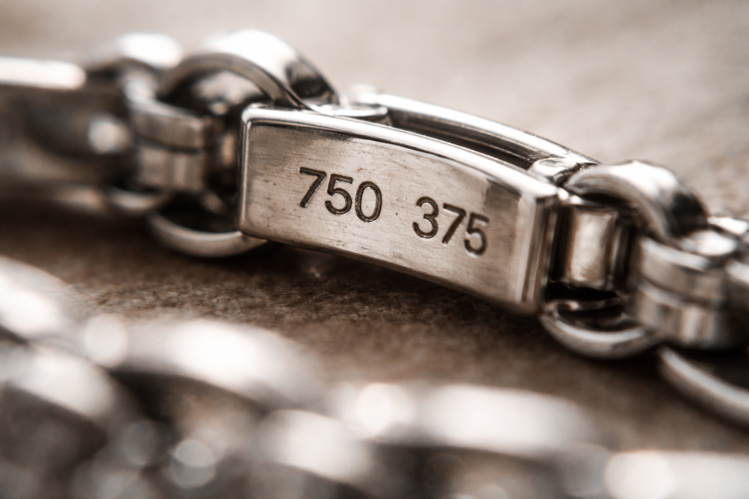 Macro photo of 750 and 375 fineness marks on a white gold bracelet clasp