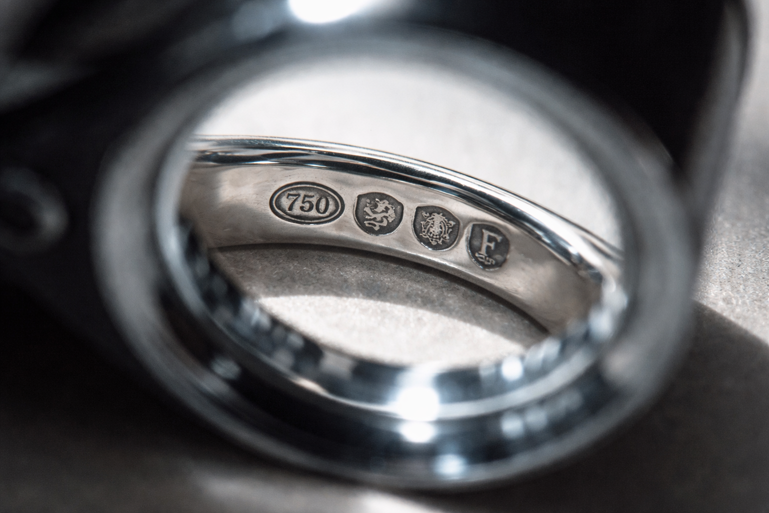 Close-up of UK hallmarks on a white gold ring under a loupe